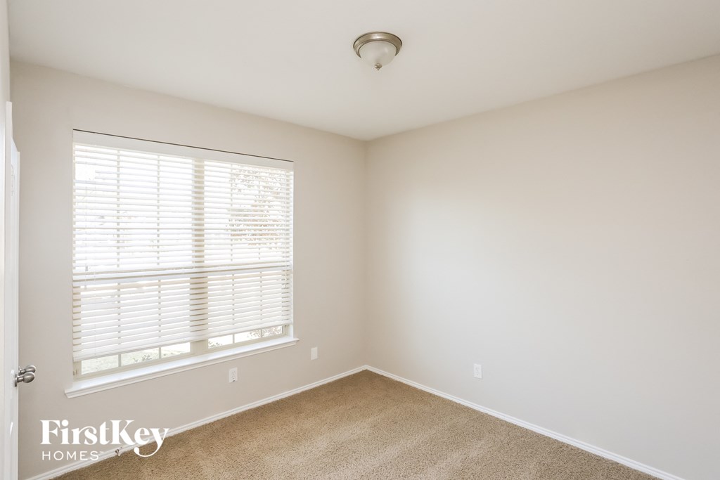 a bedroom with a large window and a carpet