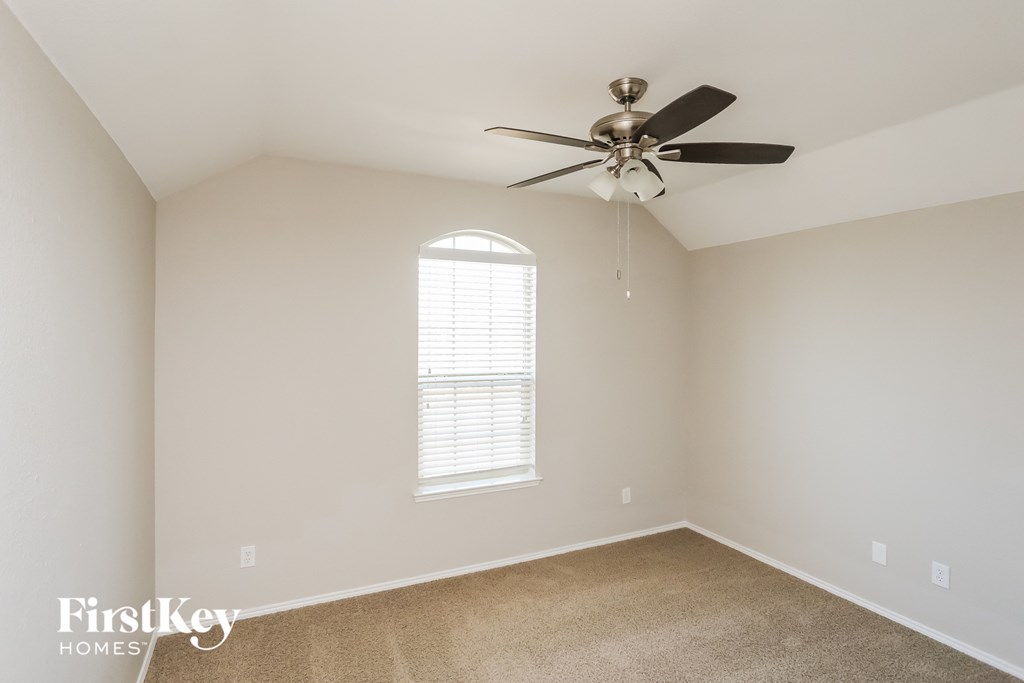 a bedroom with white walls and a ceiling fan
