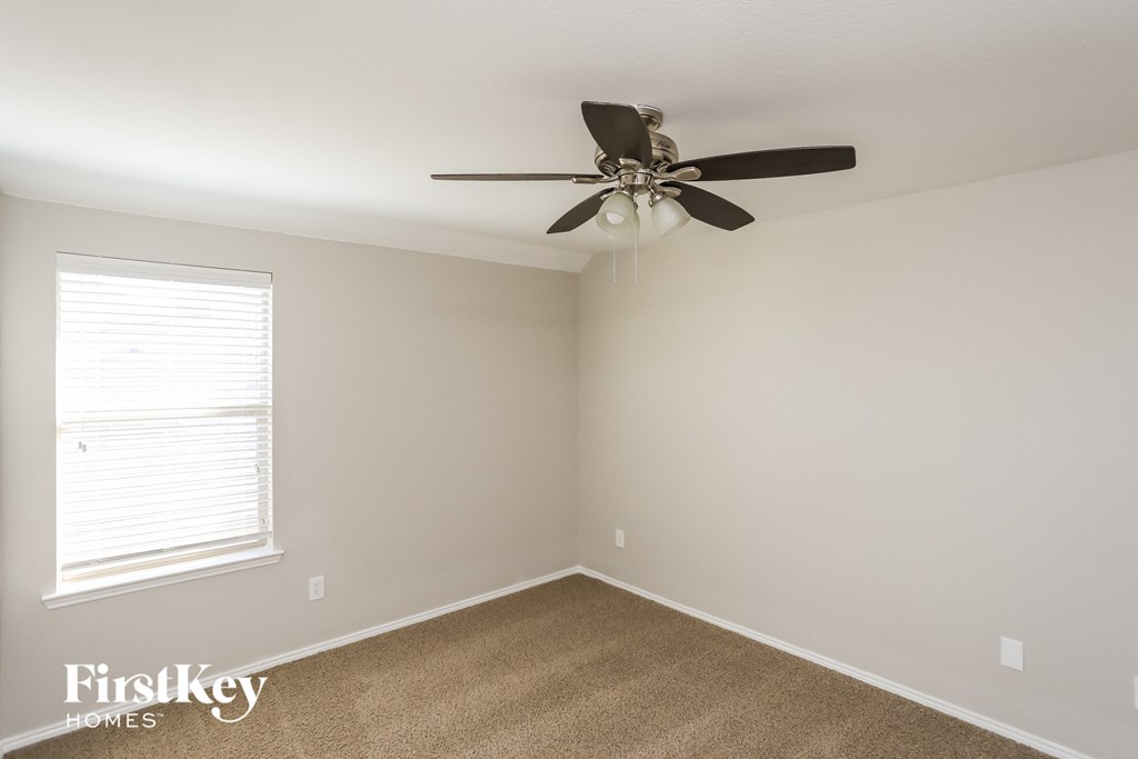 an empty room with a ceiling fan and a window