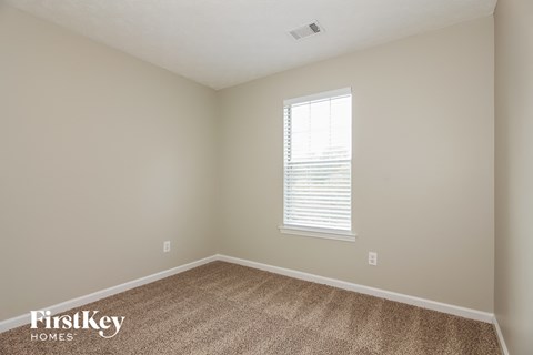 a bedroom with a carpet and a window