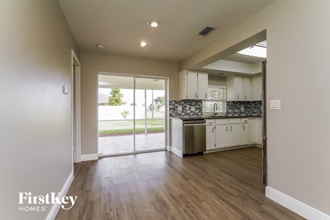 a kitchen with white cabinets and stainless steel appliances and a sliding glass door