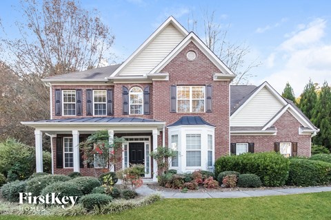 A brick house with a white porch and a sign that says "FirstKey Homes".