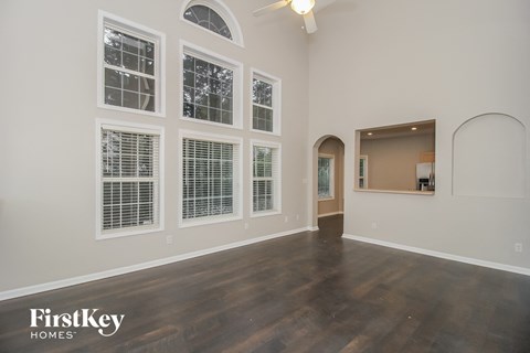 A spacious room with wooden floors and a large arched doorway.