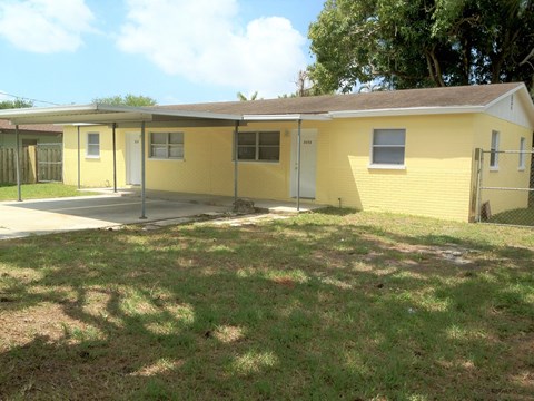 the front of a yellow house with a yard in front of it