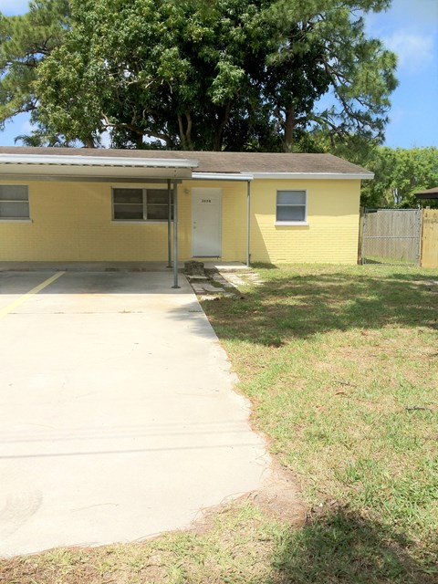 a small yellow house with a sidewalk in front of it