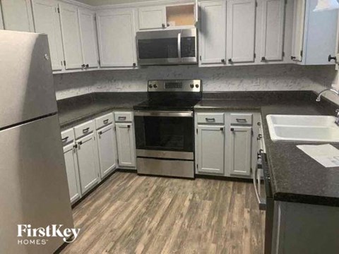 A kitchen with wooden floors and white cabinets.