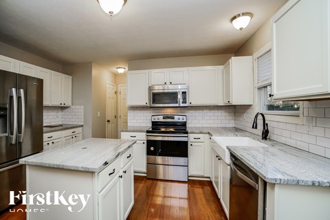 A kitchen with white cabinets and a marble countertop.