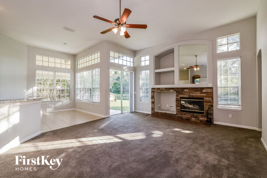 A spacious living room with a fireplace and a ceiling fan.