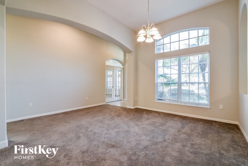 A spacious room with a carpeted floor and a large window.