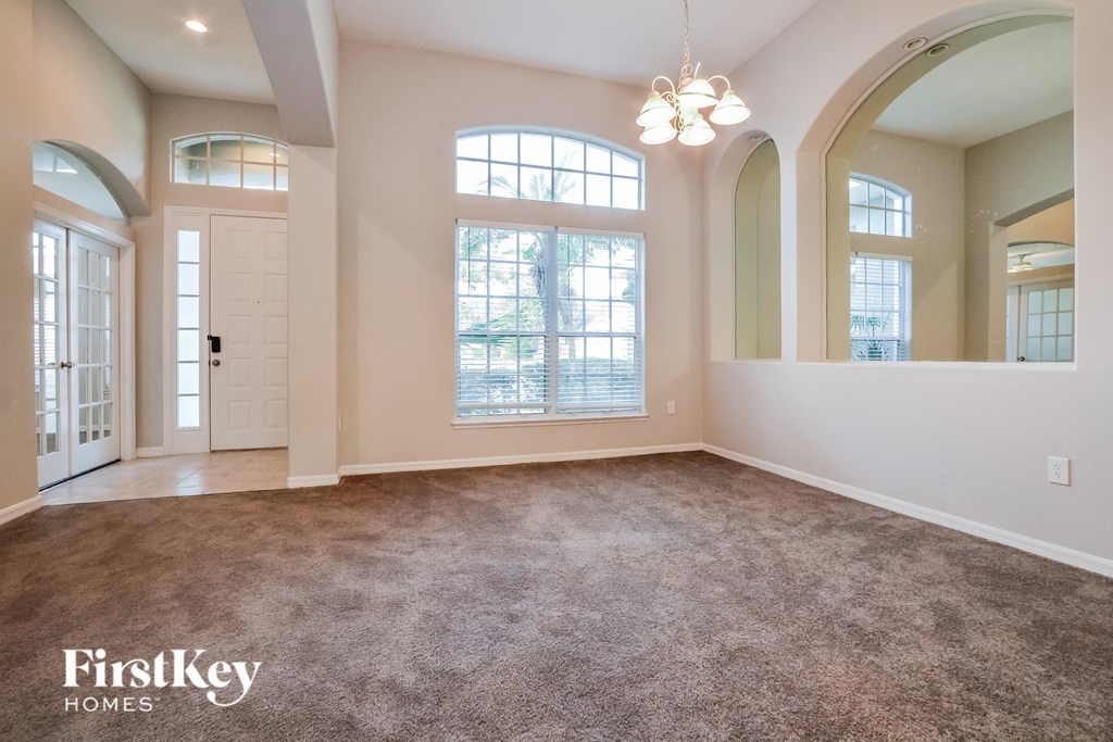 A spacious room with a carpeted floor and a chandelier hanging from the ceiling.