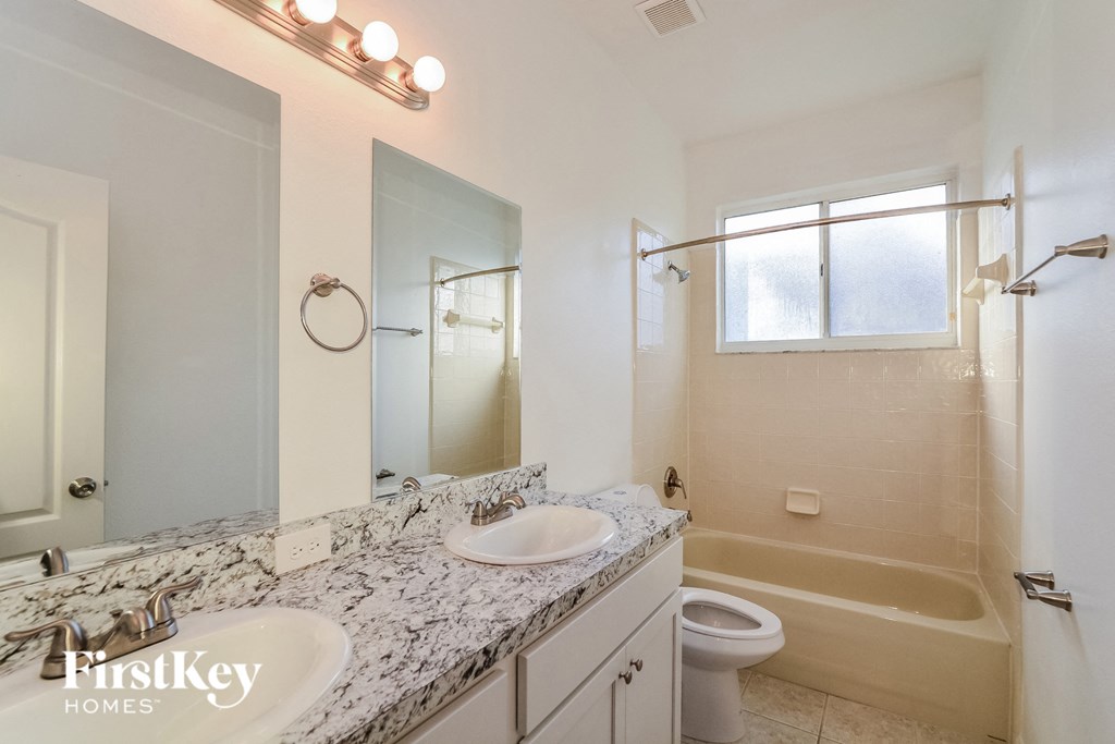 A bathroom with a marble countertop and a large mirror.