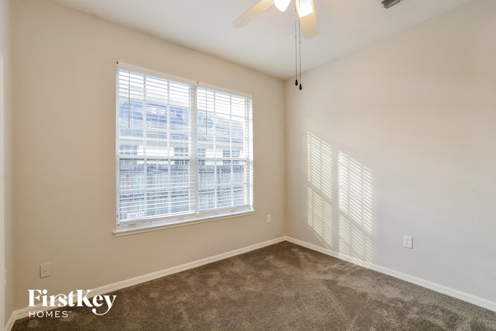 A room with a carpeted floor and a window with blinds.