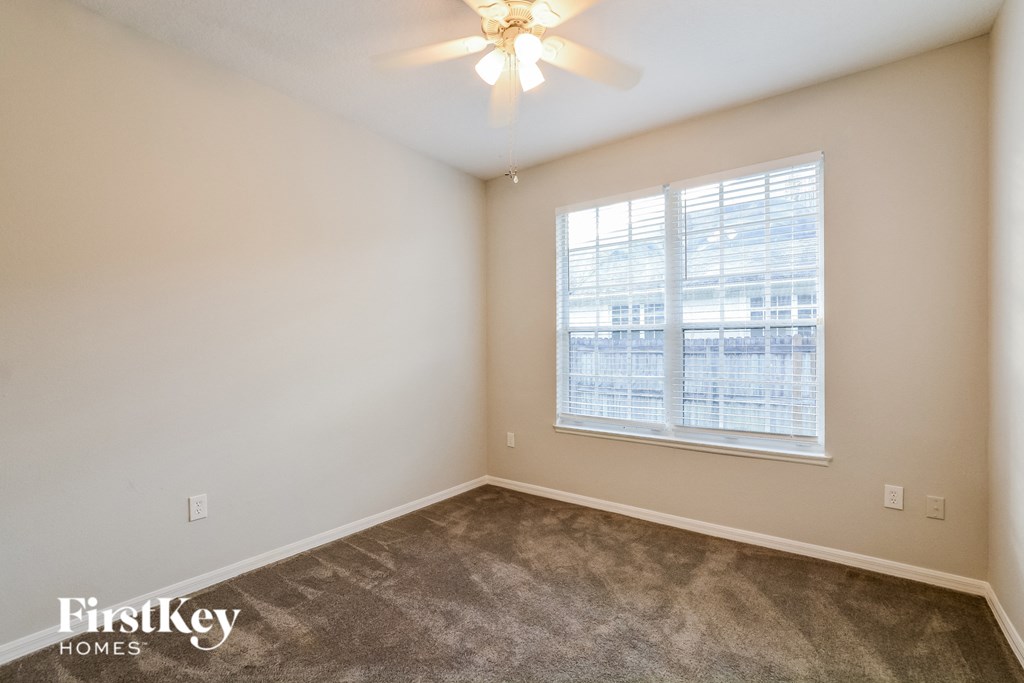 A room with a carpet floor and a window with blinds.