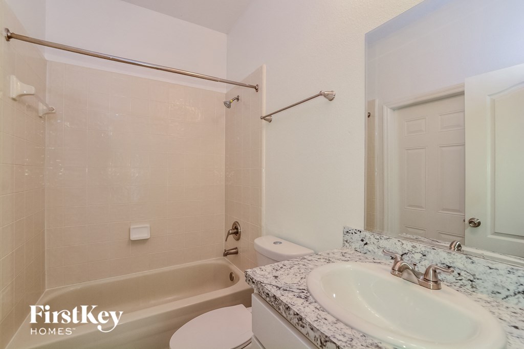 A bathroom with a marble countertop and a white bathtub.