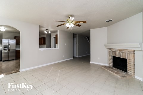 A spacious living room with a fireplace and a ceiling fan.