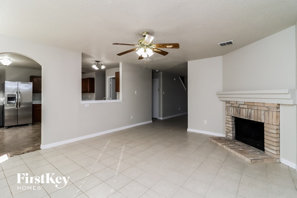 A spacious living room with a fireplace and a ceiling fan.