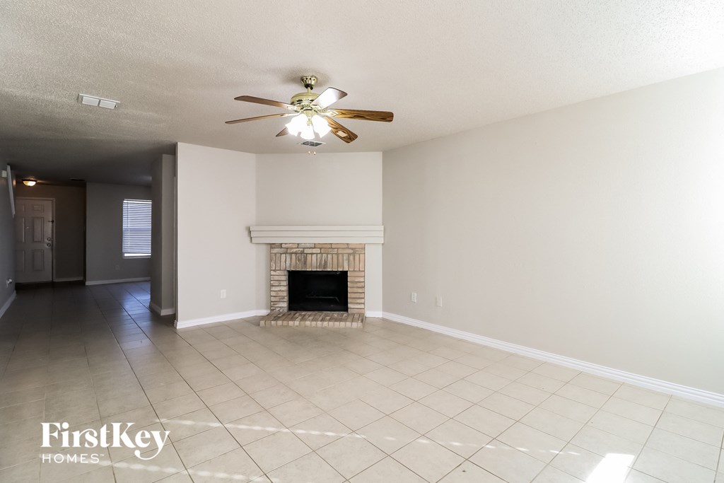 A spacious living room with a fireplace and a ceiling fan.