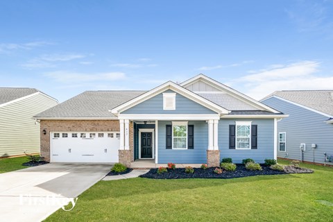 a blue house with a white garage door and a lawn