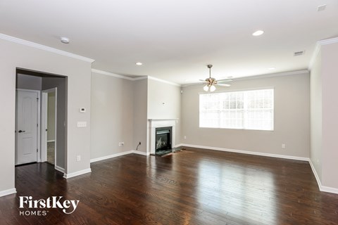 an empty living room with a fireplace and a ceiling fan