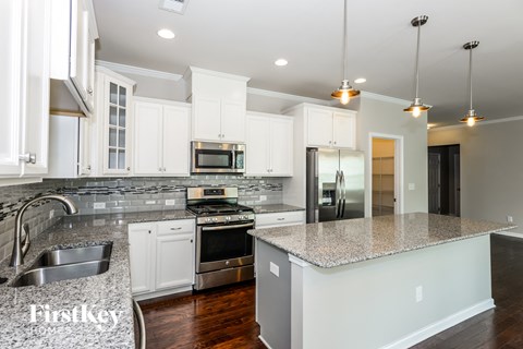 a white kitchen with granite counter tops and stainless steel appliances