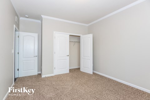 a bedroom with two closets and two doors and a carpeted floor