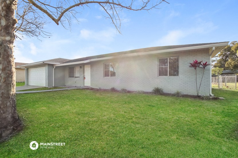 a white house with a lawn and a tree