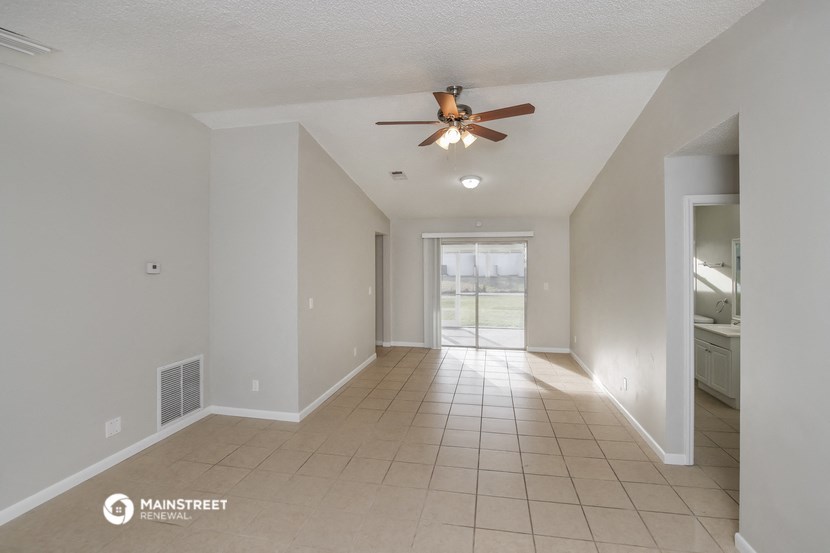 an empty living room with a ceiling fan and a tiled floor