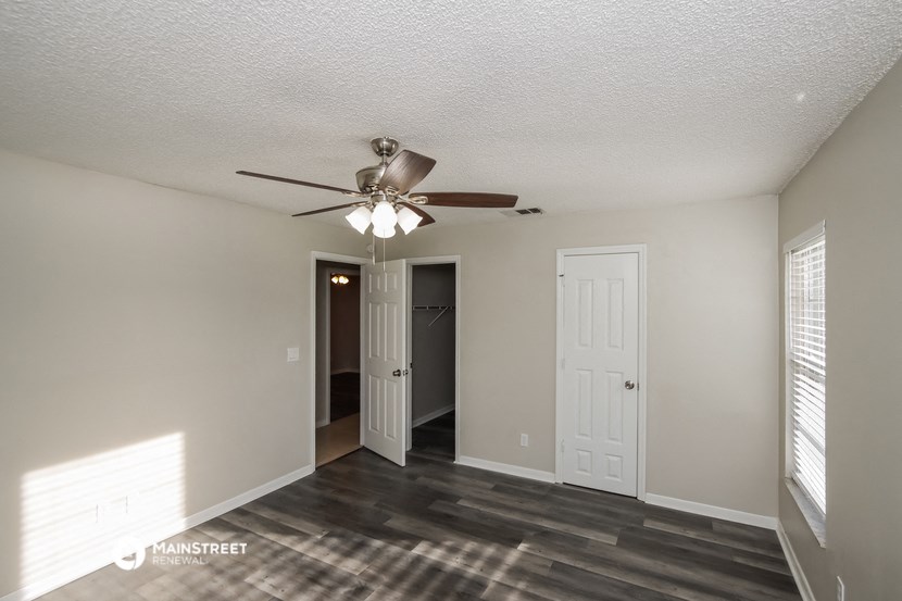 a living room with a ceiling fan and a door to a hallway