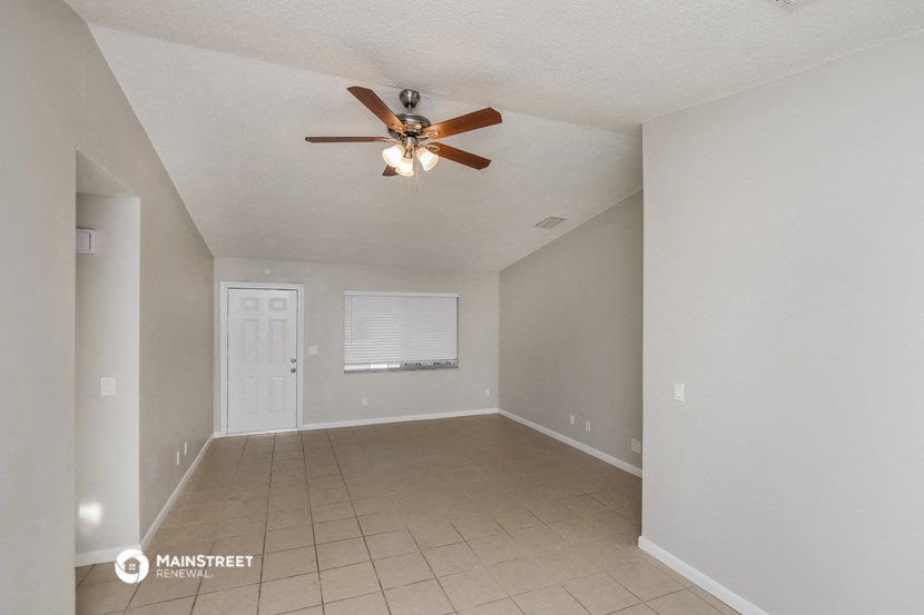 an empty living room with a ceiling fan