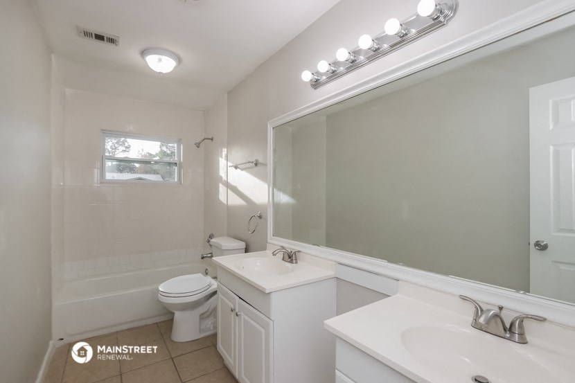 a white bathroom with a large mirror and a toilet and sink