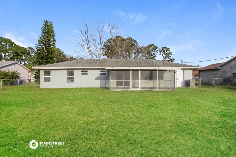 a small white house with a grassy yard and a fence