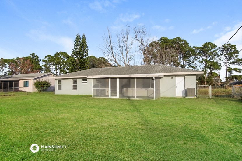 a small white house with a yard and a fence