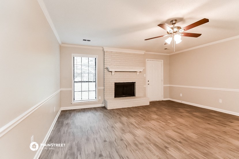 an empty living room with a ceiling fan and a fireplace