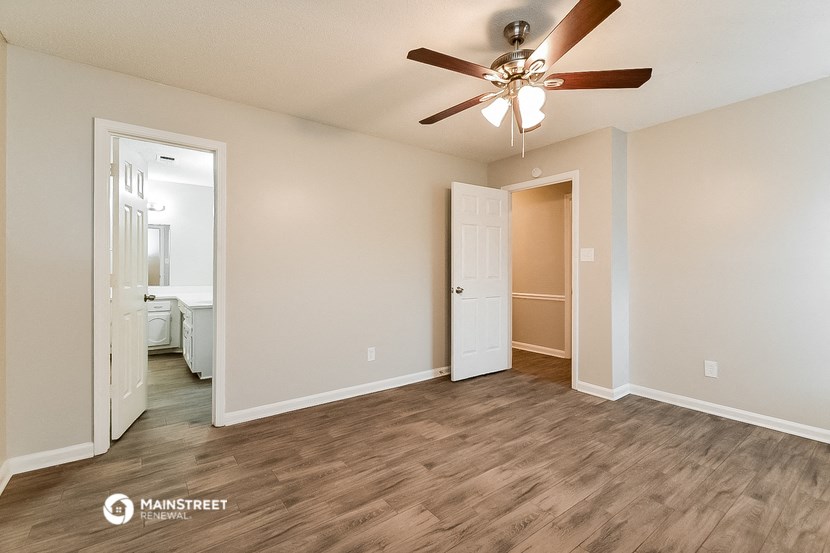 a living room with a ceiling fan and a door to a bathroom