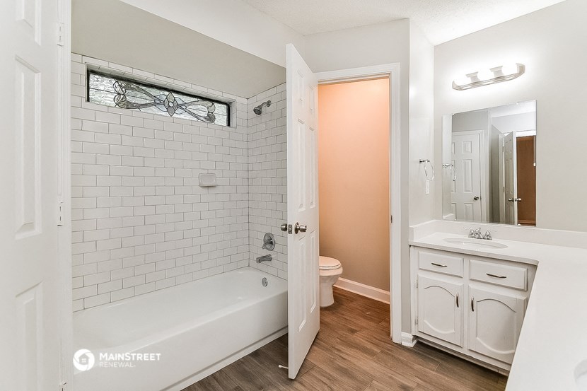 a white bathroom with a tub and a sink and a mirror
