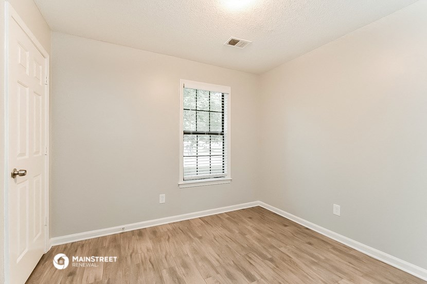 the spacious living room with hardwood flooring and a window