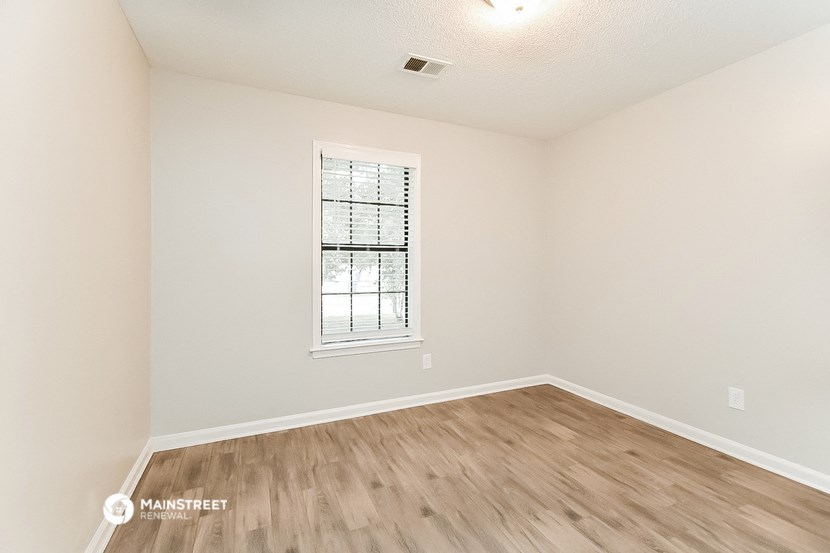 the spacious living room with hardwood flooring and a window