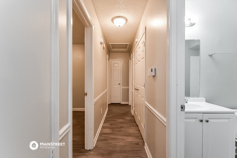 a hallway with white cabinets and a white sink and a hall way with a door