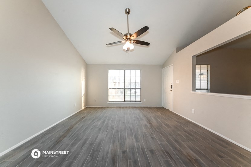 an empty living room with a ceiling fan and a window