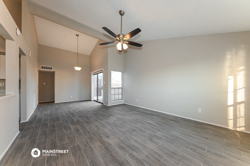 an empty living room with wood flooring and a ceiling fan