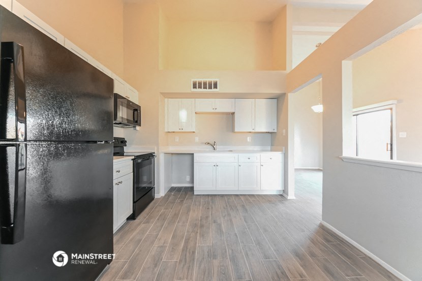 an empty kitchen with white cabinets and a black refrigerator
