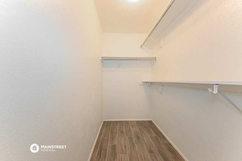 a spacious closet with white walls and wood flooring and a shelf on the wall