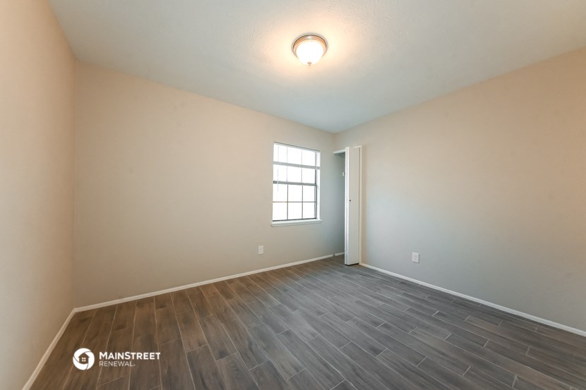 the spacious living room with wood flooring and a window