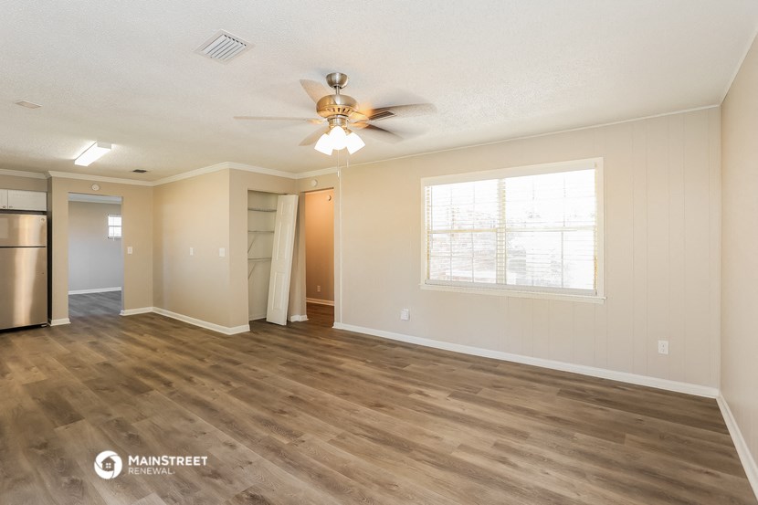 an empty living room with a ceiling fan and a window
