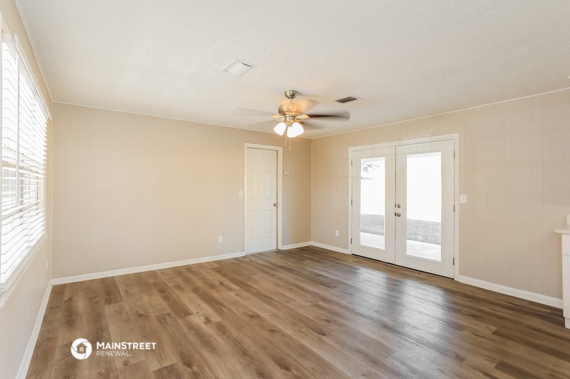 an empty living room with a ceiling fan and window