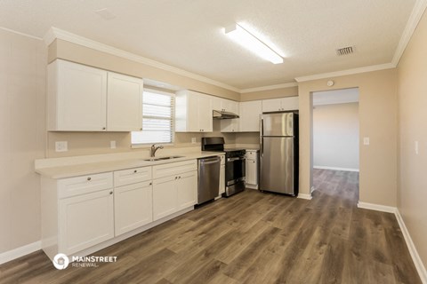 the kitchen of an apartment with white cabinets and stainless steel appliances