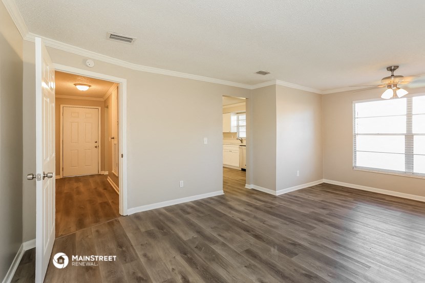 the spacious living room with hardwood flooring and a door to the bathroom