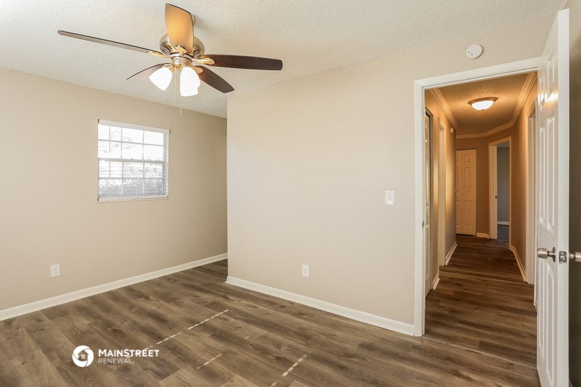 the living room and hallway of an empty house with a ceiling fan