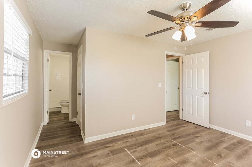 a living room with a ceiling fan and a door to a bathroom