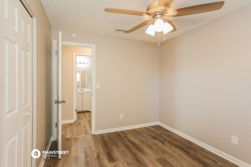 an empty room with a ceiling fan and a door to a bathroom